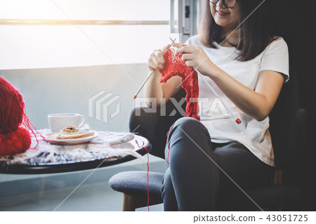 Close up shot of young woman hands knitting a red scarf handicra Close up shot of young woman hands knitting a red scarf handicra 43051725