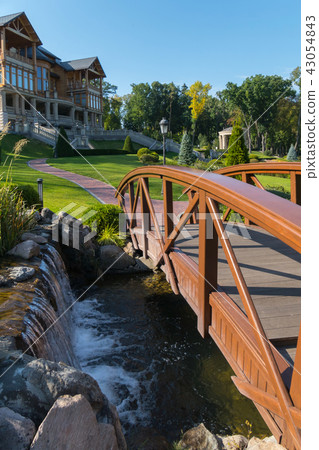 wooden bridge with railings through a stony river 43054843