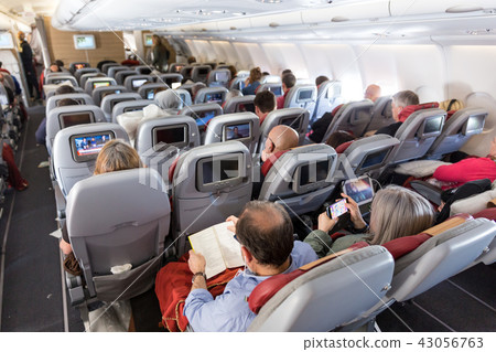 Interior of large commercial airplane with passengers on their seats during flight. 43056763