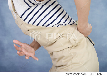 A woman complaining of low back pain A woman complaining of low back pain 43056926