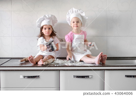 Two Little girl preparing cookies in kitchen at home Two Little girl preparing cookies in kitchen at home 43064006