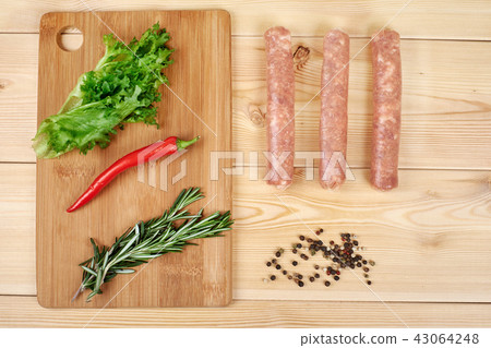 Raw sausages with vegetables and spices on wooden background 43064248