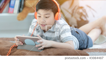 Asian boy lying and Playing Game On Digital Tablet At Home Asian boy lying and Playing Game On Digital Tablet At Home 43064487