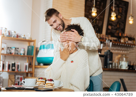 Blonde-haired man closing eyes his girlfriend making surprise Blonde-haired man closing eyes his girlfriend making surprise 43064789