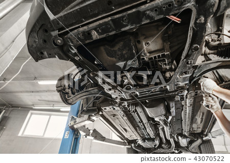 Car mechanic inspecting car wheel and repair suspension detail. Lifted automobile at repair service 43070522