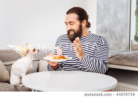 Bearded man wearing striped shirt entertaining his dog 43070739