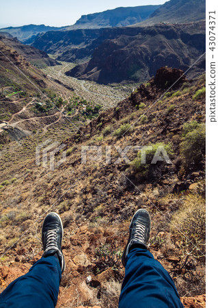 Man hiker sitting at the edge of a cliff. 43074371