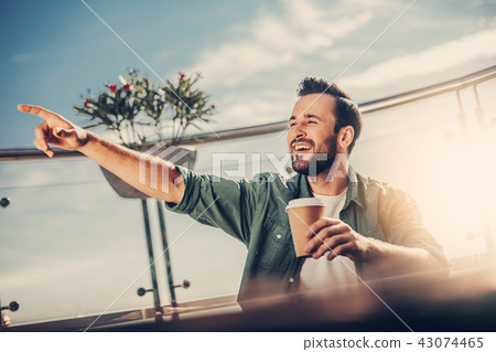 Smiling bearded man pointing finger at someone while sitting at the table Smiling bearded man pointing finger at someone while sitting at the table 43074465