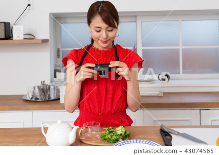 A woman taking a picture of cooking A woman taking a picture of cooking 43074565