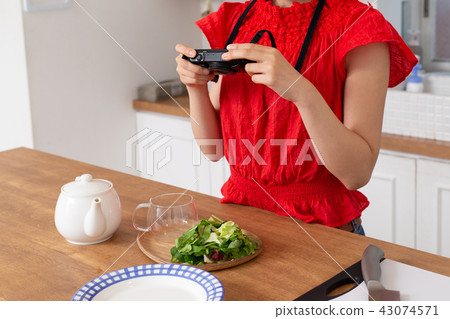 A woman taking a picture of cooking A woman taking a picture of cooking 43074571
