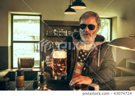 The senior bearded male drinking beer in pub The senior bearded male drinking beer in pub 43074724