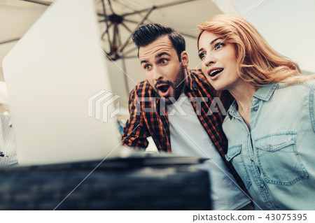 Beautiful young couple impressed by information from internet Beautiful young couple impressed by information from internet 43075395