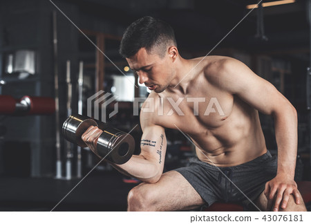 Strained man is training biceps in sport club Strained man is training biceps in sport club 43076181