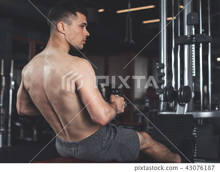 Sportsman is exercising back with equipment in gym Sportsman is exercising back with equipment in gym 43076187