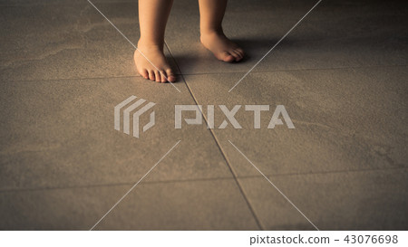 Barefoot baby are staying on heating tile floor. 43076698