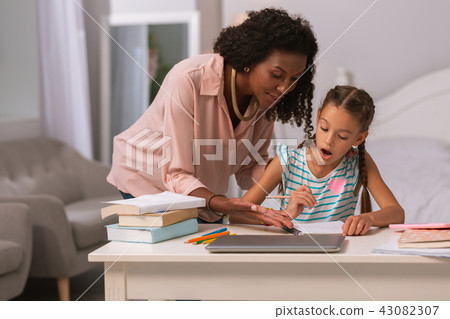 Pleasant smart woman helping her daughter at home 43082307