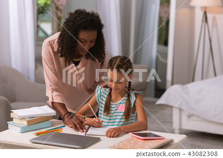 Positive smart little girl writing with mother 43082308