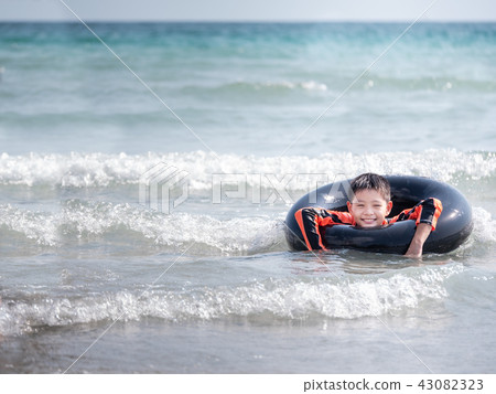 little Asian boy play waves on the beach little Asian boy play waves on the beach 43082323