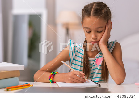 Sad school girl doing her hometask at home Sad school girl doing her hometask at home 43082324