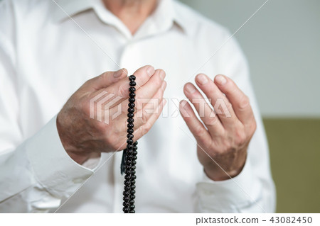 Praying hands of an old man with rosary beads 43082450