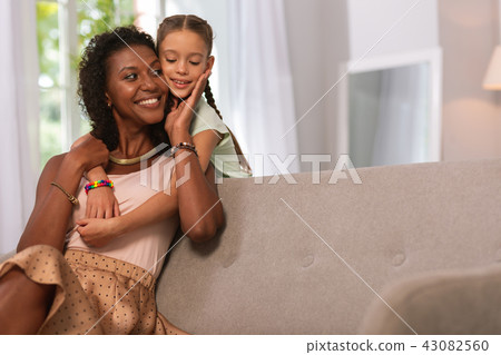 Joyful nice woman touching her daughter cheek Joyful nice woman touching her daughter cheek 43082560