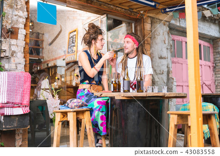 Dark-haired woman wearing long bright skirt drinking with her man 43083558
