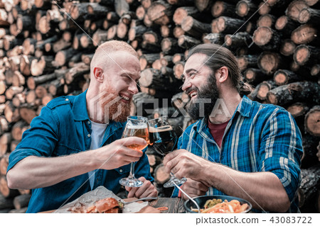 Two smiling bearded men clanging their beer glasses 43083722