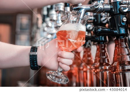 Barman holding glass while filling it with craft dark beer 43084014