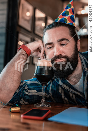 Bearded man looking at glass with dark craft beer Bearded man looking at glass with dark craft beer 43084175