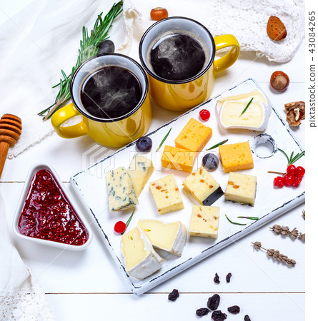 two cups of coffee and various pieces of cheese two cups of coffee and various pieces of cheese 43084265