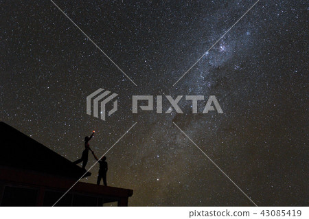 Couple on rooftop watching mliky way and catching stars in the night sky on Bali island 43085419