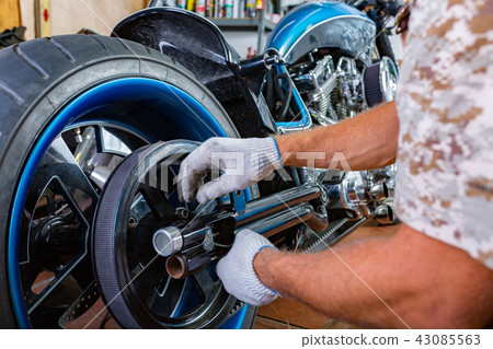 Side view portrait of man working in garage repairing motorcycle 43085563