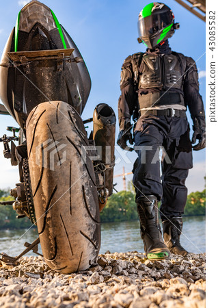 Man wearing motorcycle helmet and safety uniform sitting on bike outdoors, beautiful scenic 43085582