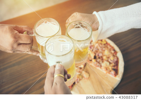 close up of hands clinking beer mugs and pizza 43088317
