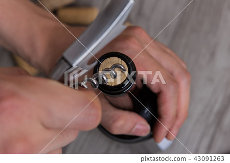一隻手用開瓶器打開一瓶酒 一隻手用開瓶器打開一瓶酒 43091263