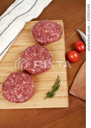 Raw cutlet of minced meat on a wooden cutting board. Raw cutlet of minced meat on a wooden cutting board. 43092449