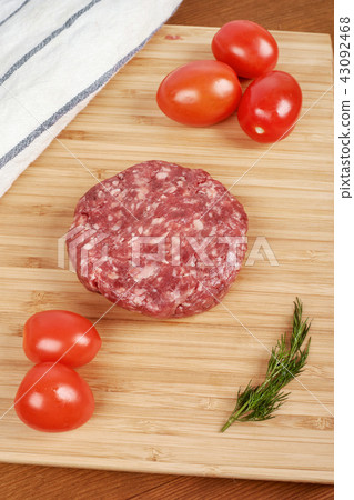 Raw cutlet of minced meat on a wooden cutting board. 43092468