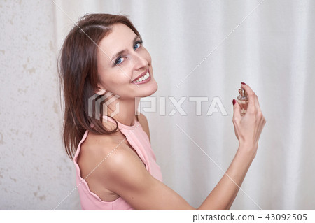 An attractive female spraying perfume on herself. 43092505