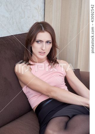 Young woman suffering from pain in leg at home. Young woman suffering from pain in leg at home. 43092542