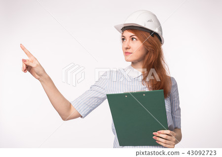 Working, engineering, people concept - Young beautiful redhead girl in architect helmet Working, engineering, people concept - Young beautiful redhead girl in architect helmet 43092723