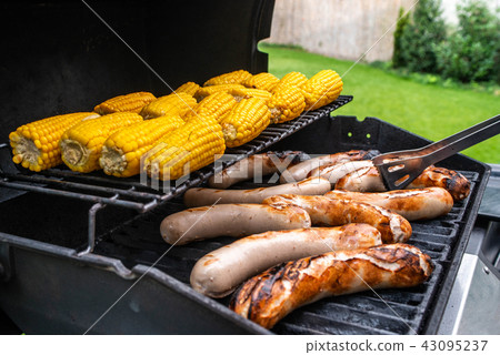 Freshly cooked sausages on a grill with corn close-up. Background of sausages made with charcoal Freshly cooked sausages on a grill with corn close-up. Background of sausages made with charcoal 43095237