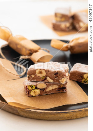 A variety of different nutty nougat in dark chocolate with roasted hazelnuts cut open to show the 43097347