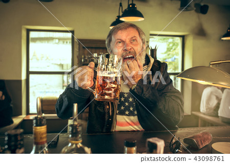 The sad senior bearded male drinking beer in pub The sad senior bearded male drinking beer in pub 43098761
