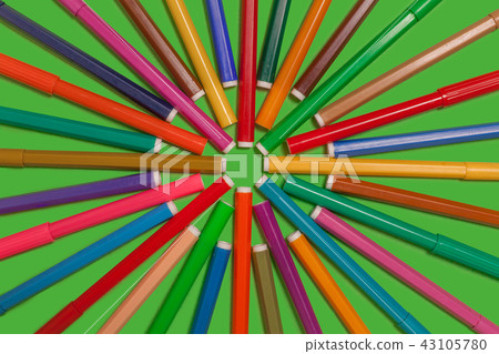 felt pens lying on a green surface forming a shape of cirlcle 43105780