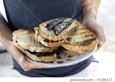 man with a plate of bread and sardines 43106327