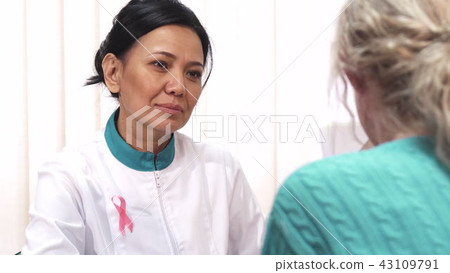 Beautiful mature female doctor talking to her patient Beautiful mature female doctor talking to her patient 43109791