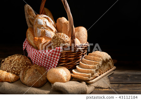 Bread and rolls in wicker basket on burlap sack 43112184