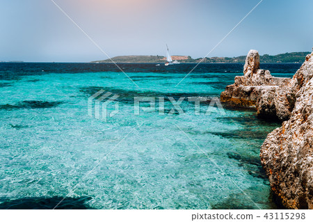Beautiful turquoise cozy bay surrounded by white cliffs. White yacht afar in the deep blue water Beautiful turquoise cozy bay surrounded by white cliffs. White yacht afar in the deep blue water 43115298