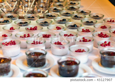 Closeup many dessert jar rowed up on buffet table with fresh fruits jelly and cream 43127907