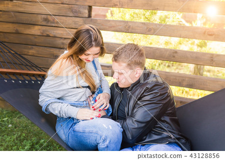 Love, pregnancy and family concept - Man hugging his pregnant wife Love, pregnancy and family concept - Man hugging his pregnant wife 43128856